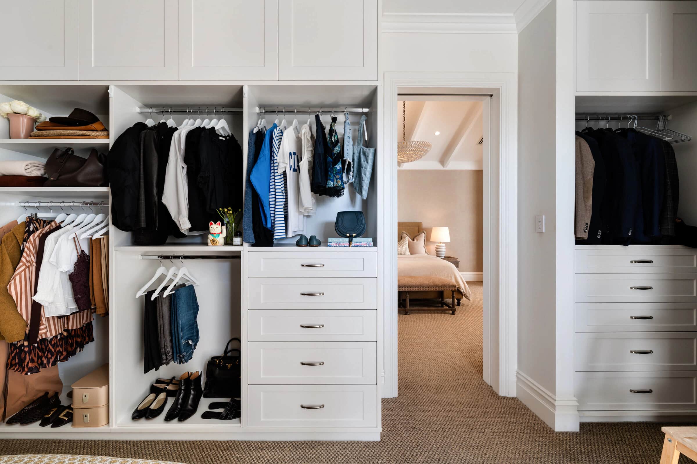 An edited wardrobe with clothes hung by colour and shoes and folded pieces on open shelves